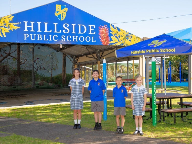 Hillside students standing in front of cola area on the grass smiling