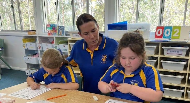 Hillside students recving one to one support from teacher at their desks.