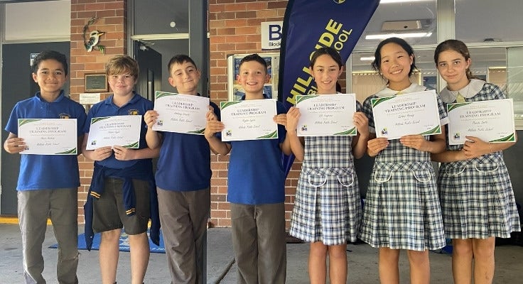 Hillside students holding assembly awards up on stage.