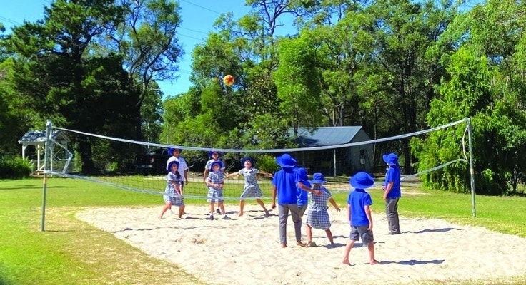 Students playing beach volleyball on the volleyball court.