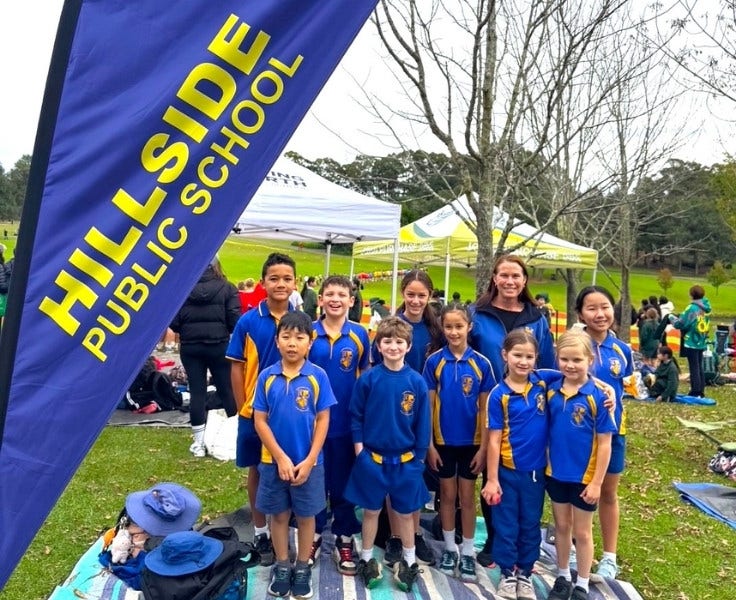 Hillside students standing on the grass smiling at Fagan Park