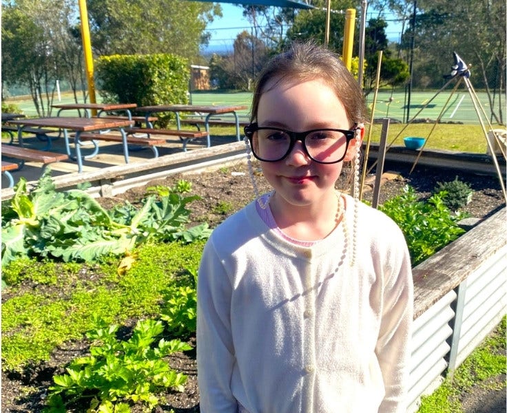 Hillside student smiling in front of garden bed