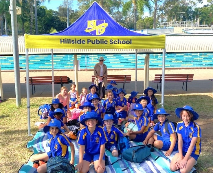 Hillside students sitting under school gazebo in front of the pool at the swimming carnival at swimming carnival
